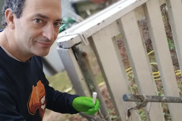 En person håller i ett provrör utomhus. Foto.